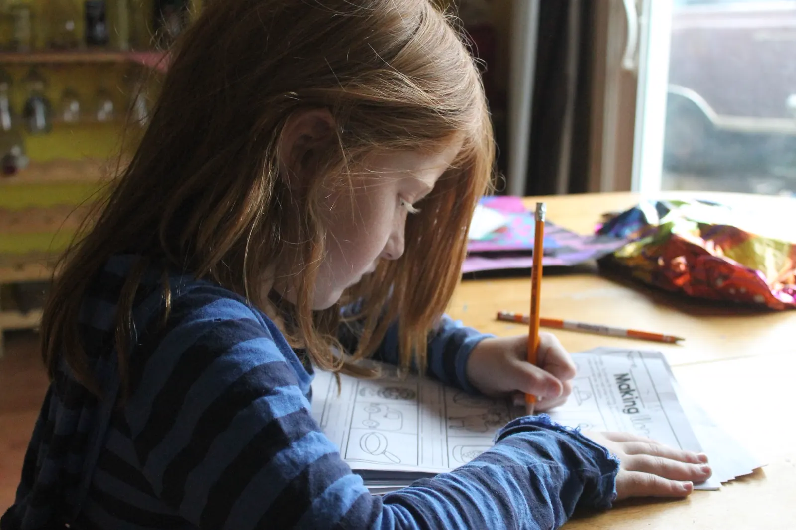 A child working on a printed worksheet at the kitchen table